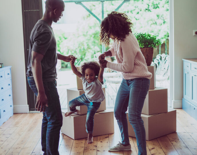 Family celebrating with child in front of moving boxes.